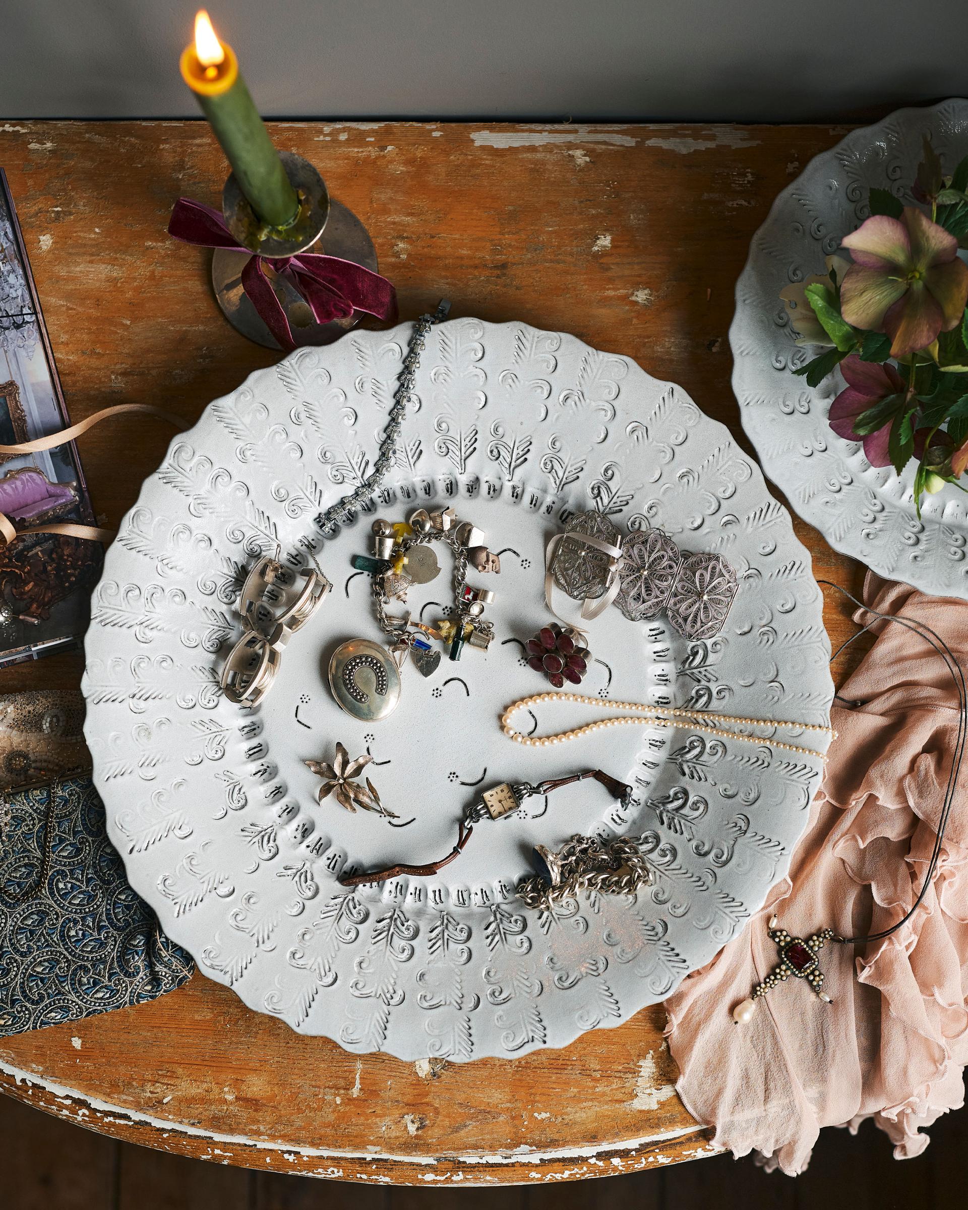 An overhead view of a large bohemian-style glossy white ceramic platter with a scalloped rim and delicate impressions and surface patterns.