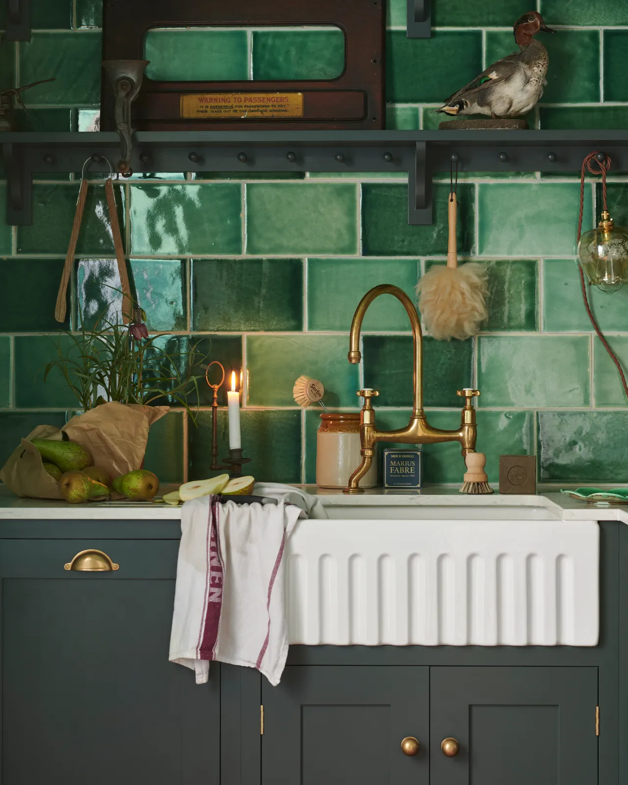 A detailed close-up of a Shaker-style kitchen, painted in 'Bakehouse Green' and fitted with glossy emerald green wall tiles.