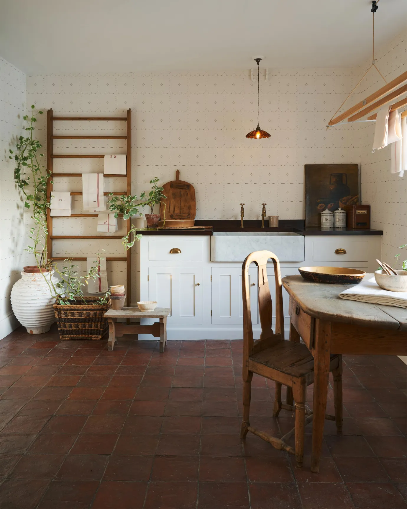 A classic English scullery room decorated with white, wooden accent and antiques that are warmed up with the Terracotta Square tile floor.